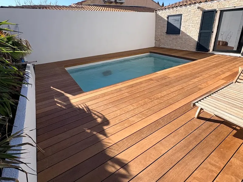 Plage de piscine en itauba dans une cour close, teinte chaude