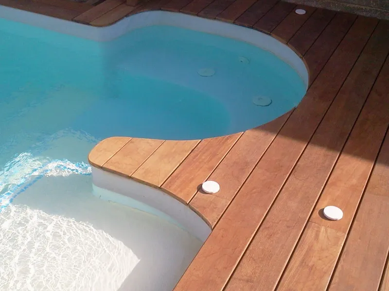 Plage de piscine en itauba avec spots encastrés autour d'un bassin arrondi